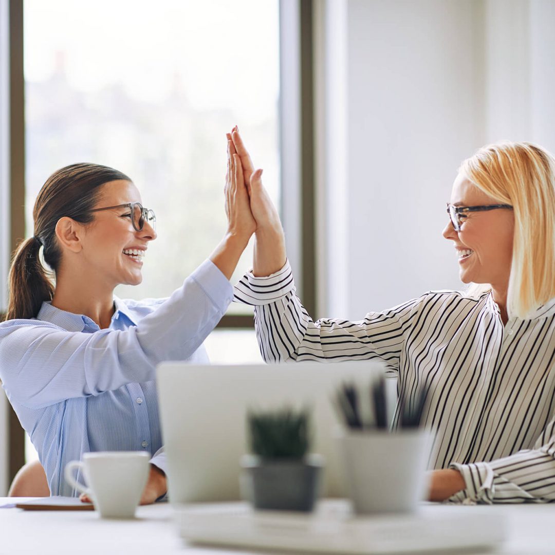 two-smiling-businesswomen-high-fiving-together-in-DDNACN5-1.jpg